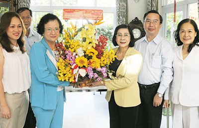 Nguyen Thi Thu Ha (yellow) send flowers to greet Associate Professor Tran Thi Trung Chien, former Health Minister, on the occasion of Vietnam Doctor’s Day (Photo: SGGP)