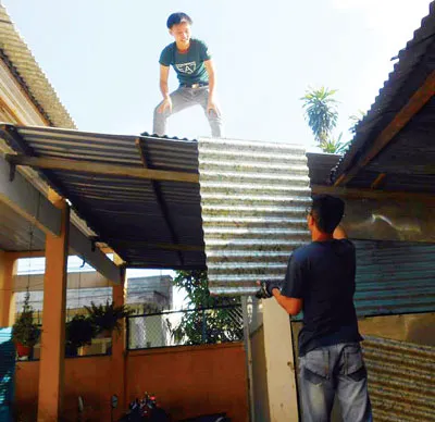 Lực lượng tình nguyện viên tham gia hoạt động cải tạo mái tôn trường bằng tấm lợp sinh thái tại Trường Tiểu học Mỹ Huề huyện Hóc Môn.
