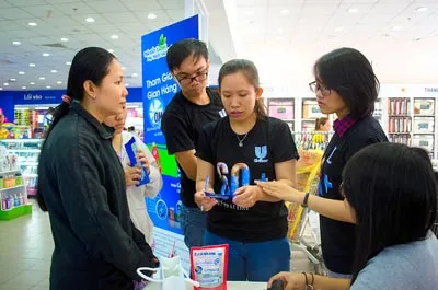 Các tình nguyện viên tư vấn cho người tiêu dùng thực hiện thu đổi vỏ hộp sữa để tái chế thành tấm lợp sinh thái, tại TPHCM.