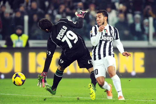 Carlos Tevez (phải, Juventus) đưa bóng qua tay thủ thành Gianluca Pegolo trong trận lượt đi.
