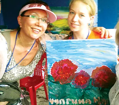 Du khách chụp ảnh lưu niệm sau khi thực hiện xong tác phẩm nghệ thuật tại xưởng vẽ của họa sĩ Nguyễn Duy Hiền.