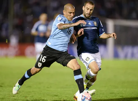 Maximiliano Pereira (trái, Uruguay) tranh bóng với Rodrigo Palacio (Argentina).