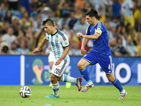 Tiền đạo Sergio Aguero (trái) đi bóng trước sự đeo bám của hậu vệ Emir Spahic.