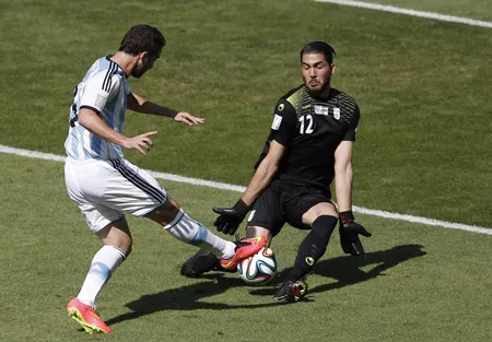 Gonzalo Higuain (trái, Argentina) trong một pha đối mặt với thủ môn Alireza Haghighi (Iran)