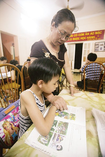 Retired teacher Vu Thi Ngoc Oanh is teaching a needy child to read ( Photo : SGGP)