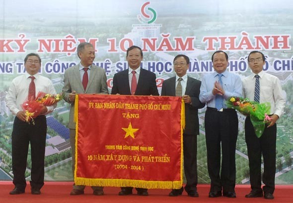 HCMC Secretary of Party Committee Le Thanh Hai ( 2 from right ) offers the national flag to the director board of HCMC Biological Technology Center.(Photo:SGGP)