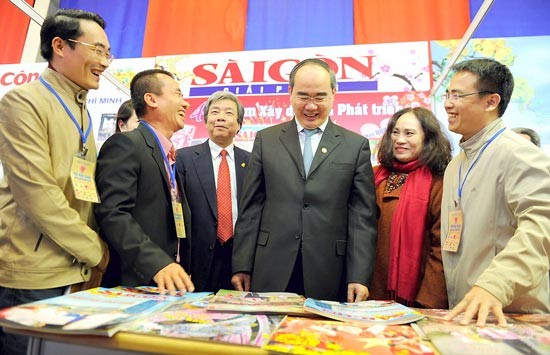 Mr. Nguyen Thien Nhan ( third, L), Member of the Politburo and Chairman of Vietnam Fatherland Front Central Committee visits Sai Gon Giai Phong Newspaper's display booth. (Photo:SGGP)
