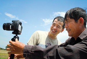 Sharing is caring: Director Trinh Dinh Le Minh shows farmer Muoi Thanh how to use a camera to film a scene. — Photo courtesy of YouFarm Facebook page