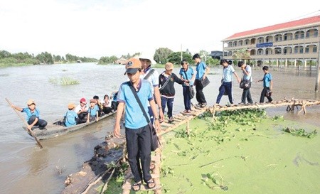 Students battle through floods to get to junior high school in the southern province of Long An. Of the 1,468 junior high schools in the Mekong Delta, only 384 meet national standards. — VNA/VNS Photo Trang Duong