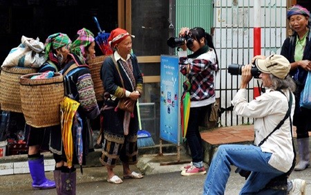 Tourists take photos of ethnic people in Sa Pa Town, Lao Cai Province. Deputy PM Nguyen Xuan Phuc said HCM City should encourage tourism enterprises to co-operate with localities in the north-west region. (Photo: VNA/VNS)
