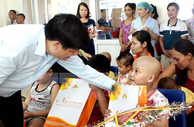 Deputy Minister of Health Nguyen Thanh Long (L) presents gifts to children with cancer in September 2015 (Photo: VNA)
