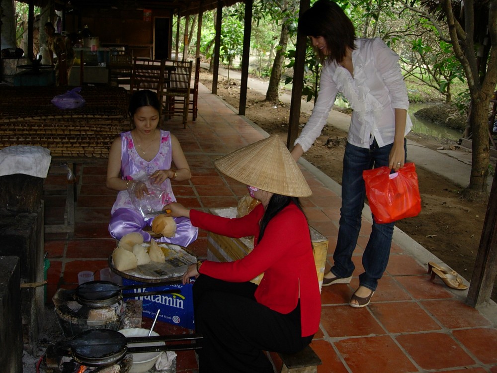 Visitors enjoy the process of making a folk cake at a tourists area in Can Tho. (Photo: KK)