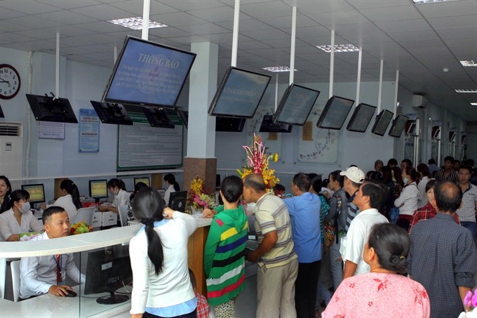 People read notices of raising medical fees in a hospital of HCM City’s Thủ Đức District. The Ministry of Health was asked yesterday to ensure 90 per cent of the country’s population is covered by health insurance by 2020.