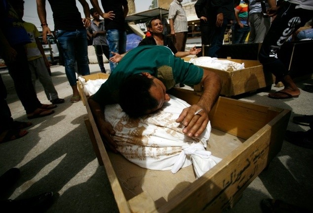 Iraqi men mourn over bodies after they lost five members of their family in a suicide bombing that ripped through Baghdad’s busy shopping district of Karrada, during a funeral Najaf, on Sunday. — AFP/VNA Photo