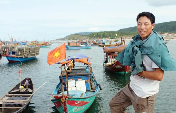 A fisherman by his boat in Ha Tinh province (Photo: SGGP)