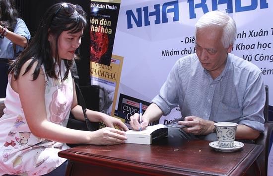 Vietnamese American astrophysicist Trinh Xuan Thuan (R) offers books to reader. (Photo:SGGP)