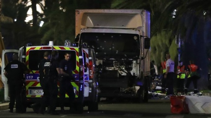 Police officers and rescued workers stand near a van that ploughed into a crowd leaving a fireworks display in the French Riviera town of Nice on July 14
