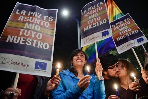 Colombians hold signs reading Peace is my, your, our business and celebrate in Bogota as they watch on a giant screen the signing of the agreement at the conclusion of the peace talks between the government and the FARC on August 24, 2016. – AFP/VNA