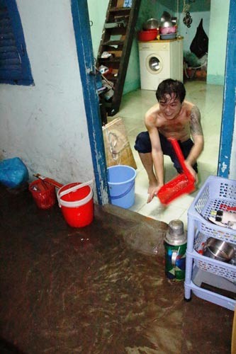 Residents in Binh Chanh District bail rainwater out of their house (Photo: SGGP)