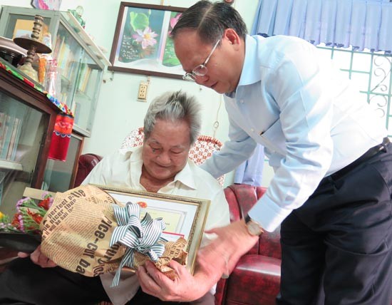 Deputy Standing secretary of HCMC Party Committee Tat Thanh Cang gives merit certificate to Ms Minh in District 8-Photo: SGGP