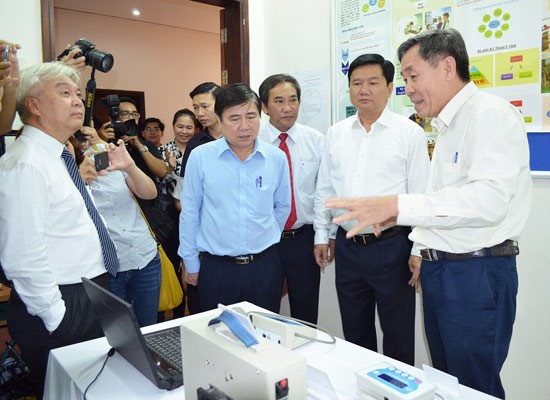 Professor Vo Van Toi (R) introduces biomedical engineering equipment to HCMC leaders at HCMC International University (Photo: SGGP)