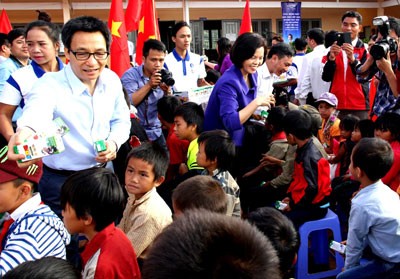 Deputy PM Vu Duc Dam gives milk to students (photo: SGGP)