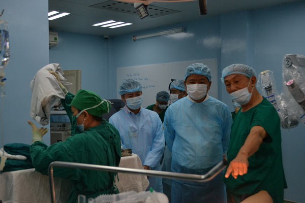 Party Chief Thang ( 2, R) visits the hospital before doctors carry out the endoscope surgery by robot (Photo:SGGP)