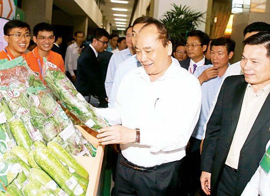 Prime Minister Nguyen Xuan Phuc visits a booth showcasing organic farming products at the conference on agricultural development in HCMC on December 18 (Photo: SGGP)