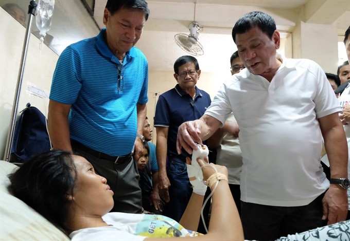 A handout photo made available by the Presidential Photographers Division (PPD) on Thursday shows Filipino President Rodrigo Duterte (right) visiting an explosion victim in the town of Midsayap, North Cotabato province, Philippines, 25 December. According to news reports on Thursday, at least 35 were injured in an explosion of two improvised explosive device (IED) at the town plaza of Hilongos, Leyte island, and six more were hurt in the town of Aleosan, North Cotabato province. — EPA/Presidential Photographers Division