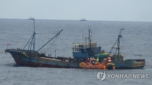 The file photo, taken on Dec. 12, 2016, shows a South Korean patrol boat (in orange) approaching a Chinese boat fishing in South Korea's exclusive waters in the Yellow Sea. (Photo courtesy of maritime police)