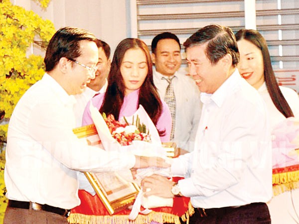 Chairman of the HCMC People’s Committee Nguyen Thanh Phong (R) gives District 1 leader certificate of merit for getting high revenue in 2016, VND10 trillion (US$439.19 million) on December 30 (Photo: SGGP)