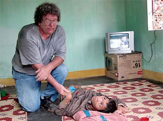 Mike kneels down beside Agent Orange victim Pham Van Thi as he shares sufferings with him