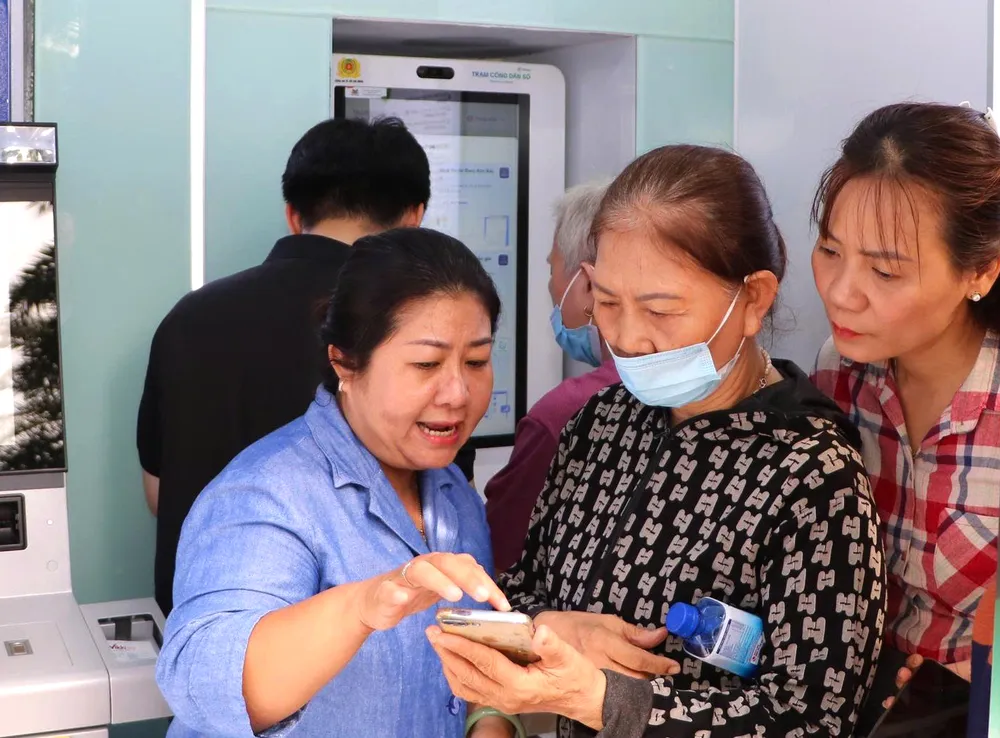 Hướng dẫn người cao tuổi cài đặt các ứng dụng tại Trạm Công dân số. Ảnh: HỒNG HẢI