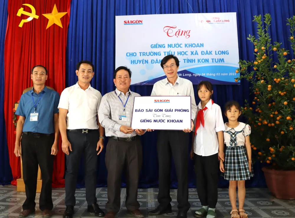 Phó Tổng biên tập Báo SGGP Phạm Văn Trường (thứ 4 từ trái qua) trao biển tượng trưng hỗ trợ xây dựng giếng khoan cho trường