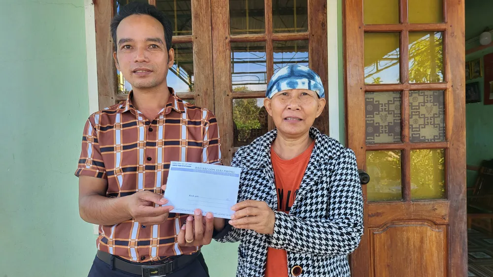 Đại diện UBND xã Đăk Năng thay mặt Báo SGGP trao tiền hỗ trợ cho bà Vân