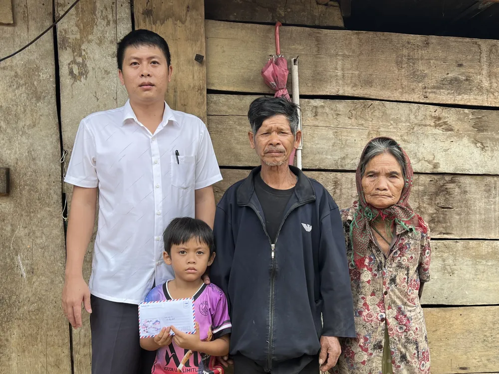 Ông Bùi Thế Toàn, Chủ tịch UBND xã Đắk Rơ Ông (ngoài cùng bên trái) trao số tiền bạn đọc Báo SGGP hỗ trợ cho gia đình cháu A Kính