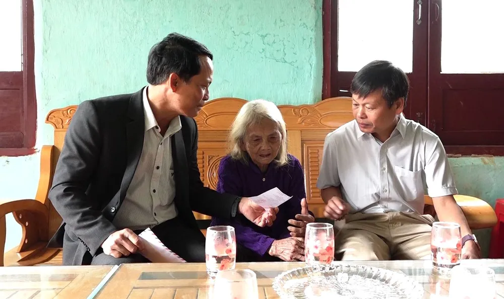 Ông Võ Trung Mạnh (bên trái), Bí thư Đảng ủy, Chủ tịch Ủy ban bầu cử xã Tu Mơ Rông, và ông Trần Quốc Huy (bên phải), Chủ tịch UBND xã, thăm, phát thẻ cử tri cho Mẹ Việt Nam anh hùng Y Tría, đồng thời động viên mẹ yên tâm chăm sóc sức khỏe