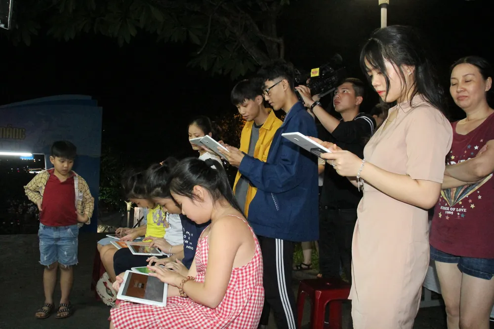 Mọi người sử dụng thiết bị ipad kết nối với máy chủ trên xe lưu động để tham gia trò chơi