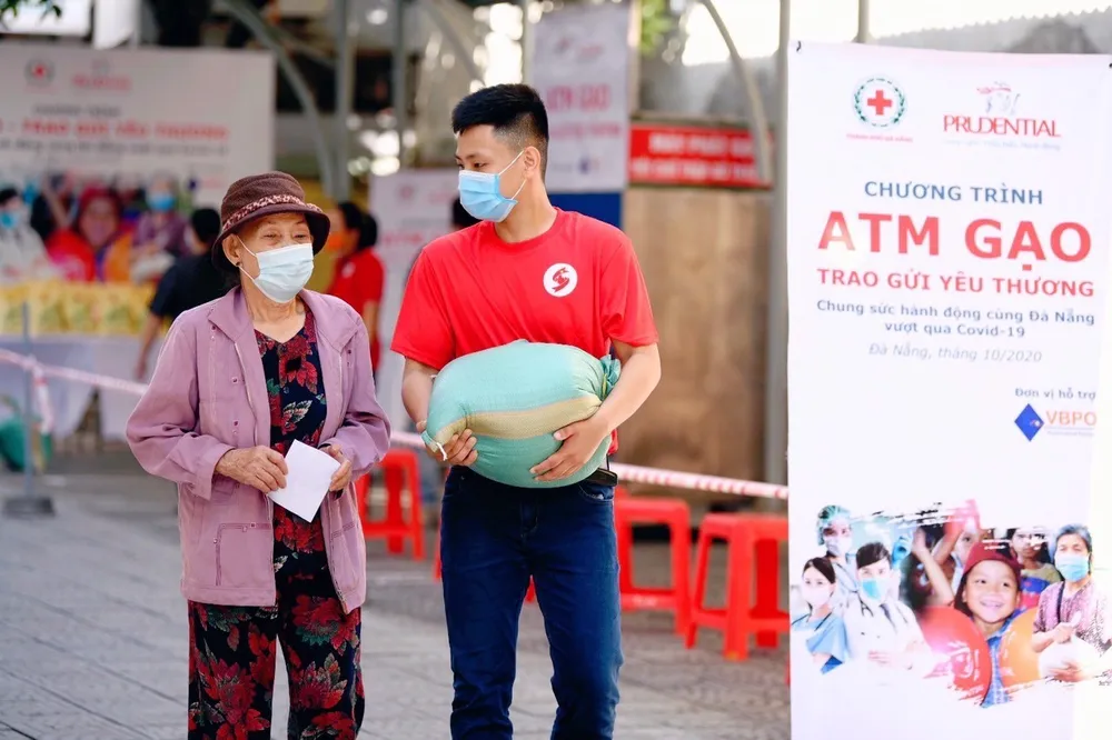 Một tình nguyện viện của Prudential Việt Nam đang giúp một người dân mang gạo