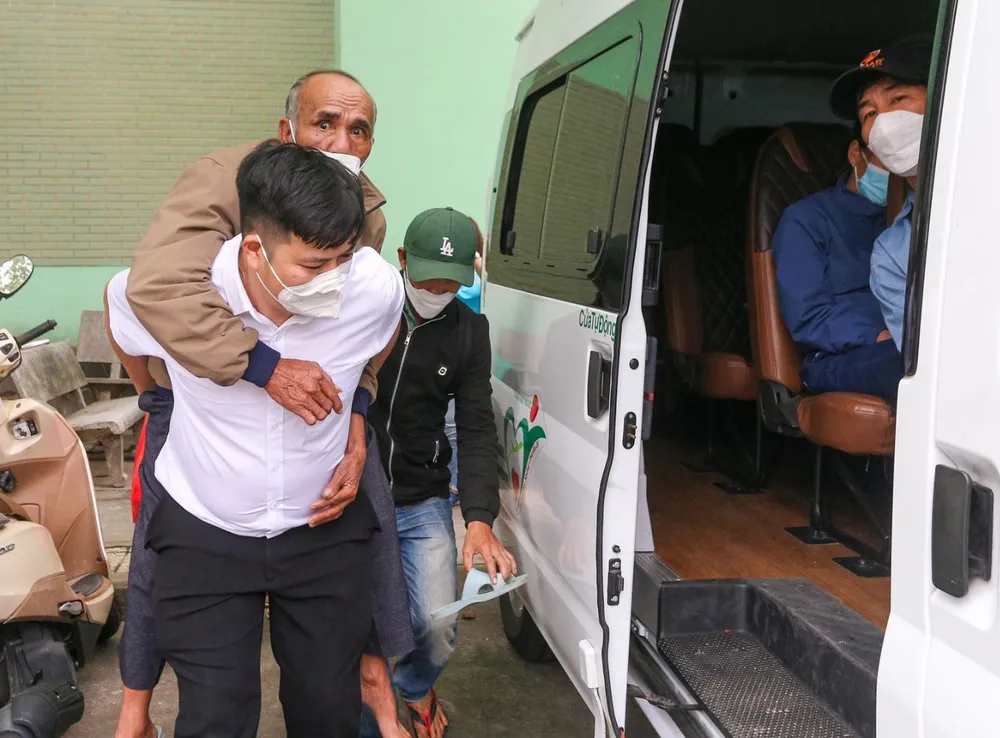 Nhân viên y tế của Bệnh viện Đà Nẵng hỗ trợ đưa các bệnh nhân lên chuyến xe nghĩa tình. Ảnh: XUÂN QUỲNH