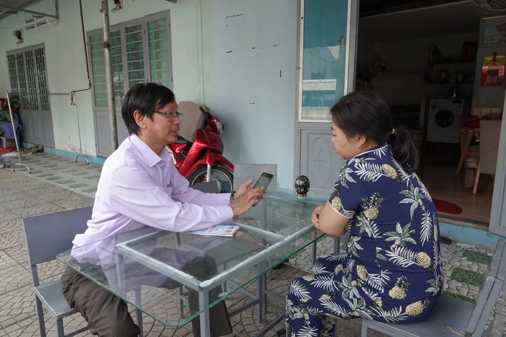 Tổ cộng đồng chuyển đổi số hướng dẫn người dân cập nhật thông tin tiêm vaccine. Ảnh: XUÂN QUỲNH