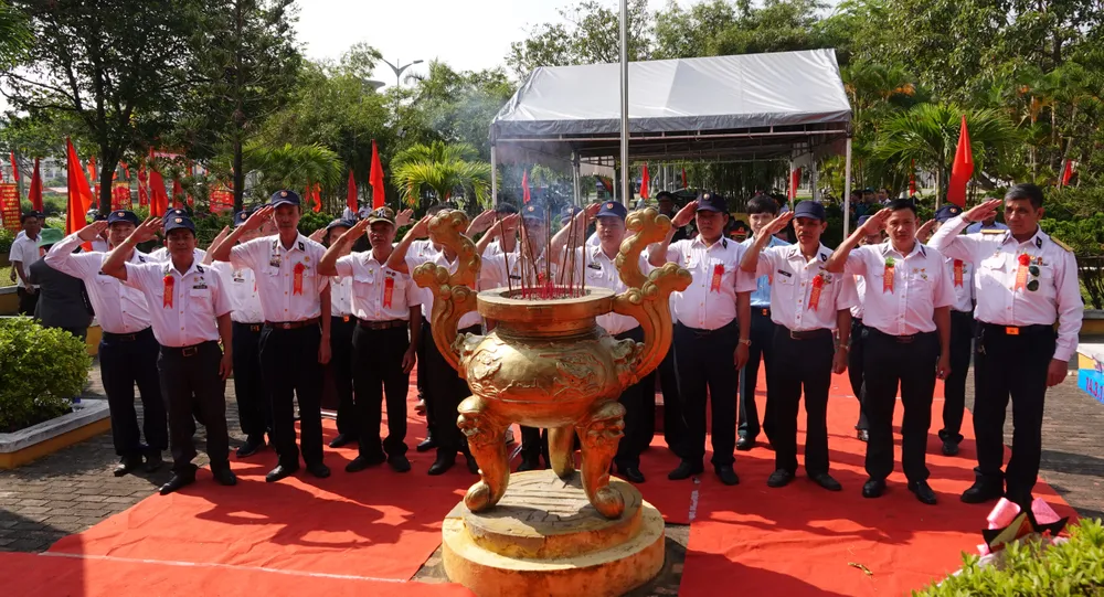 Những người đồng đội thực hiện nghi thức chào cờ để tri ân 64 liệt sĩ. Ảnh: XUÂN QUỲNH