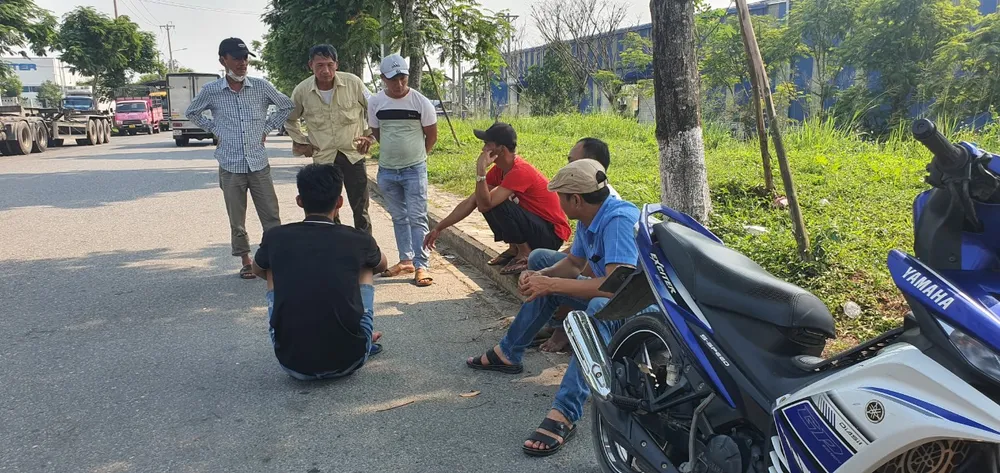 Người dân ngồi thành nhóm ở ven đường chờ đợi. Ảnh: XUÂN QUỲNH