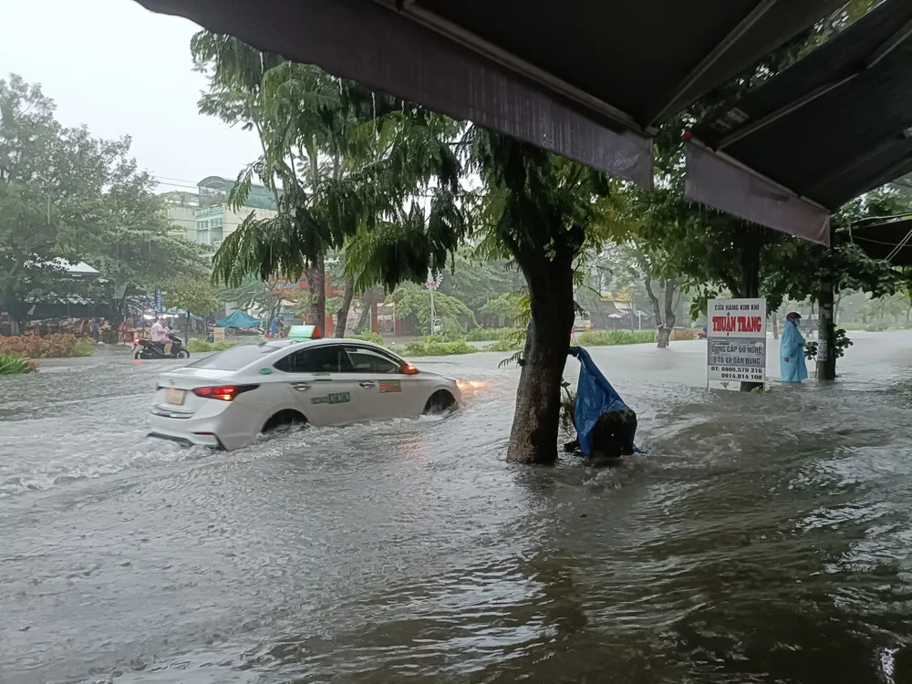 Một xe ô tô cố đi qua đường ngập lụt sâu. Ảnh: XUÂN QUỲNH