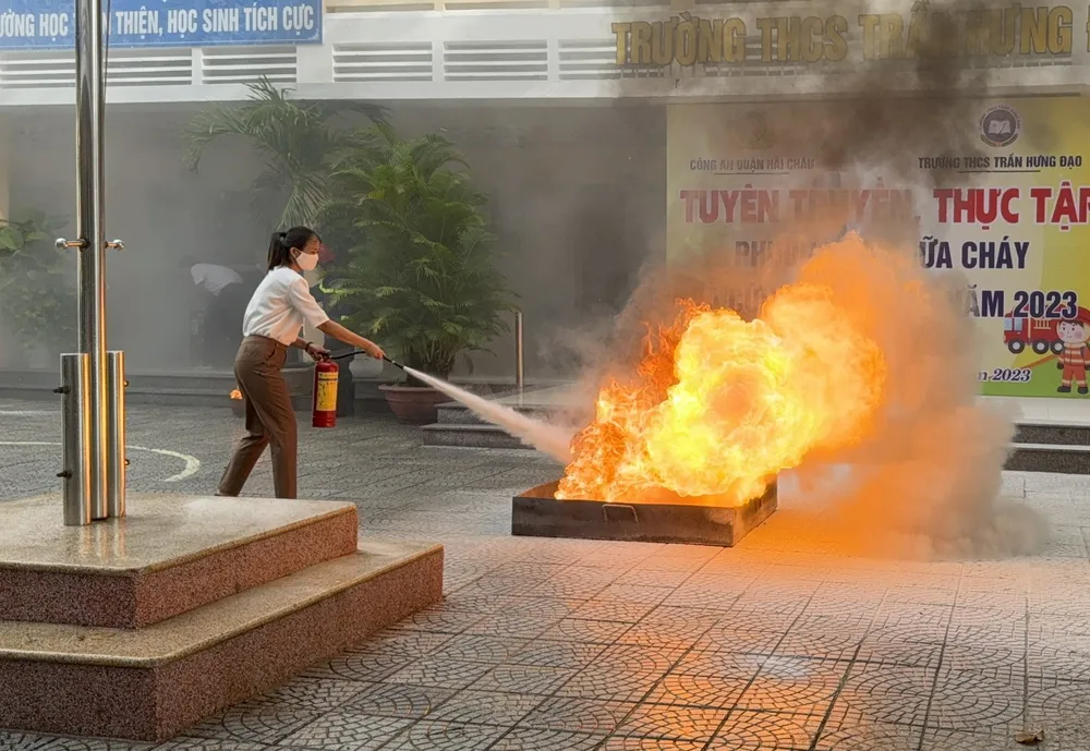 Nhân viên, giáo viên trường sử dụng bình chữa cháy để dập tắt lửa