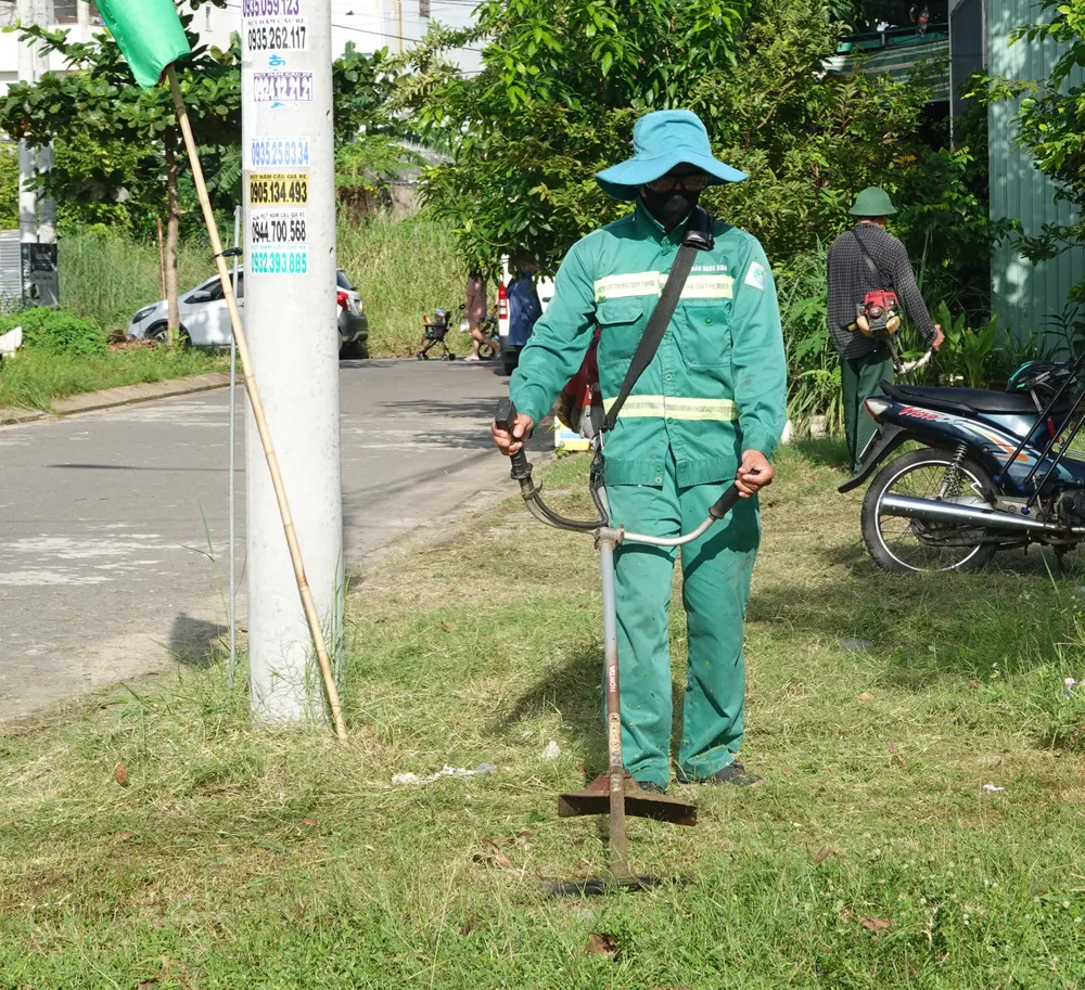 Công nhân đang phát quang bụi rậm tại Khu dân cư Quang Thành 4A, phường Hòa Khánh Bắc, quận Liên Chiểu. Ảnh: XUÂN QUỲNH
