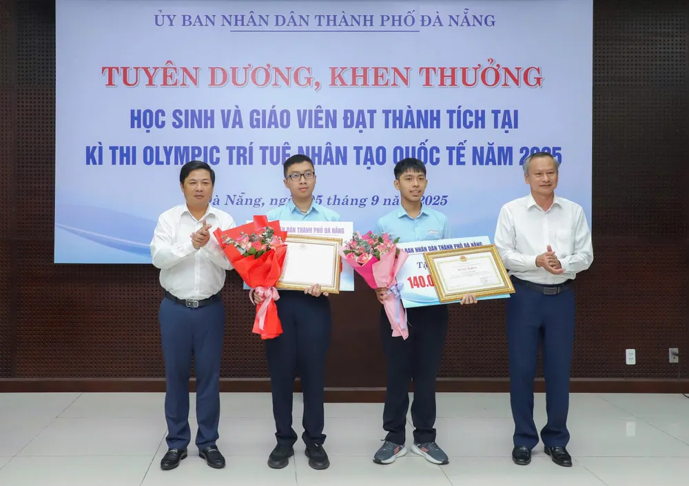 Ông Lương Nguyễn Minh Triết, Chủ tịch UBND TP Đà Nẵng và ông Đoàn Ngọc Hùng Anh, Phó Chủ tịch HĐND TP Đà Nẵng trao thưởng và tặng hoa chúc mừng 2 học sinh