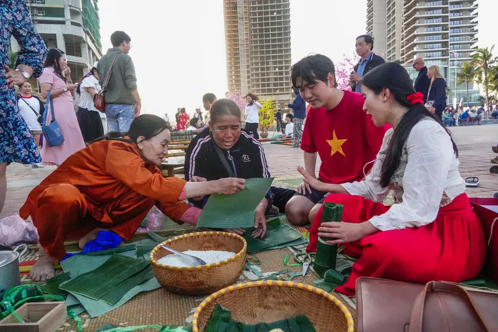 Du khách tập gói bánh tét. Ảnh: XUÂN QUỲNH
