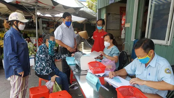 Người đi chợ Bình Thới khai báo y tế trước khi nhận phiếu đi chợ theo thứ tự trong đợt giãn cách vừa qua