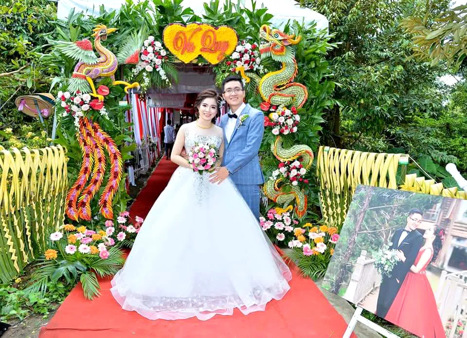 Cô dâu, chú rể chụp ảnh bên cổng cưới kết từ lá dừa, hoa, quả…